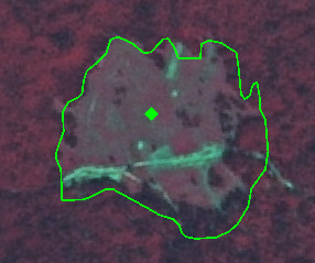 This map displays high-resolution, false-colour satellite or aerial imagery of a specific land area, likely using a Near-Infrared (NIR) composite. The background shows dense vegetation, rendered in a dark red colour, indicating healthy plant life. A distinct, irregularly shaped area of interest is delineated by a bright green outline. Within this outlined area, the land cover appears altered, displaying a mixture of lighter grey, light blue-green, and light reddish-brown tones, suggestive of bare soil, disturbed ground, or possibly low-density artificial surfaces. A small, bright green diamond marker is centrally placed within this disturbed area. No scale, compass, legend, or date information is visible.