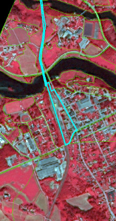 This map displays false-colour infrared (FCIR) satellite imagery of a mixed landscape. Vegetation appears in various shades of red, water bodies are dark blue or black, and urban areas or impervious surfaces are rendered in grey and light blue tones. Green lines delineate numerous land parcels or land cover/land use units across the visible area. A prominent cyan-coloured linear feature, likely representing a road or railway, traverses the map from top to bottom, crossing a large river (dark blue/black) centrally. Another cyan-coloured polygon highlights a specific rectangular urbanized or industrial block located adjacent to the river and the linear feature. The map shows a detailed view of an area featuring agricultural fields, vegetated land, a river, and urban infrastructure. No scale, compass, legend, or specific geographic location is visible.